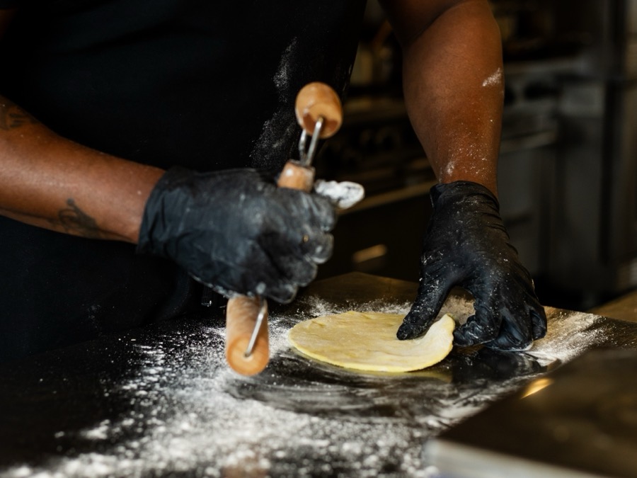 Pattie Mon rolling out a round of pattie dough on a floured counter