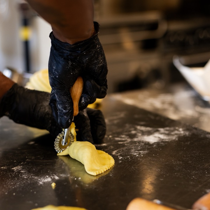 A pastry wheel crimping the edge of a folded pattie